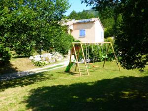 a swing set in a yard next to a house at Quiet holiday home with garden in Ponet-et-Saint-Auban