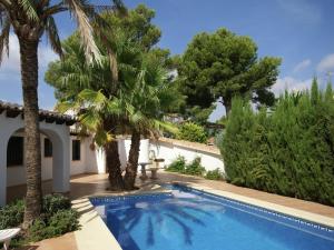 une villa avec une piscine et des palmiers dans l'établissement Nice villa in Moraira with private pool and lots of privacy, à Moraira