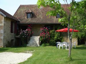 a house with two tables and a red umbrella at Cozy Holiday Home in Besse with Swimming Pool in Villefranche-du-Périgord