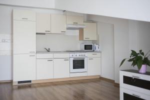 a white kitchen with white cabinets and a microwave at Olla apartmány in Svidník