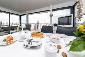 Hausboot FJORDBLIK في Kollund Østerskov: غرفة طعام مع طاولة بيضاء مع طعام عليها