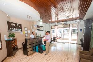 zwei Männer stehen am Hotelschalter in der Lobby in der Unterkunft Hotel America Pucallpa in Pucallpa