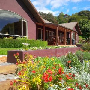 a house with a flower garden in front of it at Bush Line Lodge in Motueka