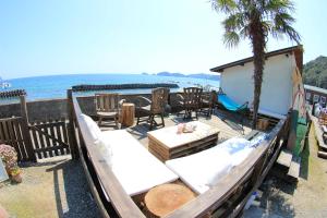 a deck with chairs and a table and a beach at PavilionSurf&Lodge in Shishikui