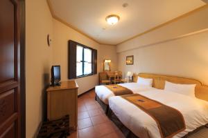 a hotel room with two beds and a television at Hotel Monterey Nagasaki in Nagasaki