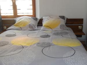 a bed with yellow and gray sheets and pillows at Gîte Pinot in Beblenheim