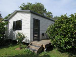 a tiny house with a porch and a deck at White Elephant Accomodation in Motueka