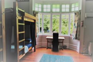 a bedroom with bunk beds and a desk and a table at White Elephant Accomodation in Motueka