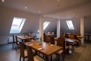 a restaurant with wooden tables and chairs and windows at Penzion Reichova vila in Valašské Meziříčí