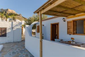 a white house with a wooden roof and a fence at Lindos SeaView Apartment in Líndos