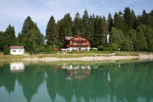 a house on the shore of a body of water at Cafe Maria - Pension - B&B in Rieden am Forggensee