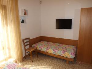 a bedroom with a bed and a chair and a flat screen tv at Albergo Dal Baffo in Lazise