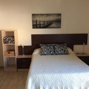 1 dormitorio con 1 cama con edredón blanco y negro en Apartamentos SOL Center Lloret, en Lloret de Mar