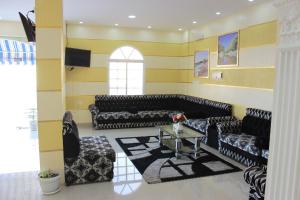 Luluat Al Afia Hotel Apartments في صور: غرفة معيشة مع أرائك سوداء وطاولة