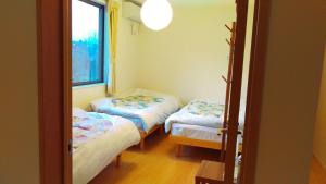 two twin beds in a room with a window at Uchi Matsushima Guesthouse in Matsushima