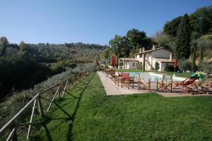 a pool with chairs and a house in the background at Casa Vacanze Vecciano in Montefalco