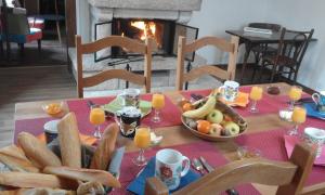 a table with a breakfast of bread and fruit and juice at Alex Guest House in Dozulé