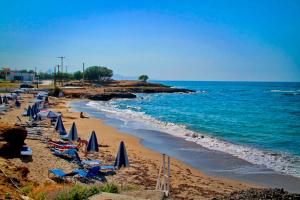 a beach with chairs and umbrellas and the ocean at Sea View Beachfront Villa Maria in Gouves