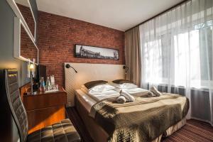 a bedroom with a bed and a brick wall at Hotel Delta in Kraków