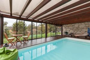 a swimming pool with a table and chairs and windows at Casa dos Colados in Fafe