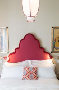 um quarto com uma cabeceira vermelha e uma cama branca em La Fonderia Firenze em Florença