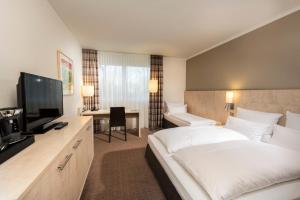 a hotel room with a bed and a flat screen tv at Mercure Hotel Bielefeld Johannisberg in Bielefeld