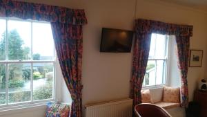 a room with two windows with curtains and a tv at The Silverdale Hotel in Silverdale