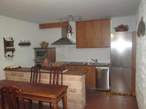 a kitchen with a table and a stainless steel refrigerator at serranía del tajo in Peñalén