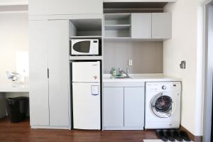 a white kitchen with a washing machine and a microwave at Residence Mumum Hotel in Busan
