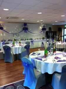 a banquet room with white tables and blue chairs at The Fitzwilliam Hotel in Rotherham