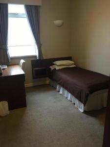 um quarto com uma cama, uma secretária e uma janela em The Fitzwilliam Hotel em Rotherham