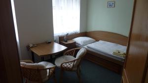 ポリチカにあるホテル THTのベッド、テーブル、椅子が備わる小さな客室です。