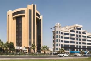 een groot gebouw met auto's geparkeerd voor het bij Ramada by Wyndham Al Khobar in Al Khobar