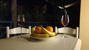 un bol de fruta en una mesa con dos copas de vino en V-Apartments, en Tsoukalaíika