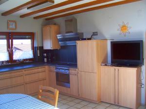 a kitchen with wooden cabinets and a flat screen tv at Ferienwohnung Abendsonne am Europa-Park in Rheinhausen