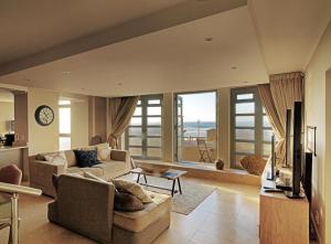ein Wohnzimmer mit Sofa und Fernseher in der Unterkunft Surferscorner Self Catering Apartments in Muizenberg