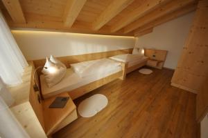 Habitación con 2 camas y suelo de madera. en Ciasa Wallis, en Badia