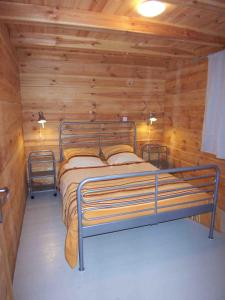 1 dormitorio con cama de metal en una cabaña de madera en Albaria Lodge, en Saint-Florent