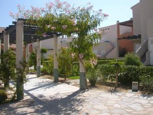 a pergola with trees and flowers in front of a building at Vera Natura Urbanización Naturista in Vera