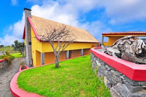 ein gelbes und rotes Haus mit einer Steinmauer in der Unterkunft Casa da Rocha in Calheta