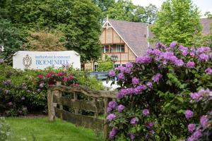 een tuin met bloemen en een hek voor een gebouw bij Landhuishotel De Bloemenbeek in De Lutte