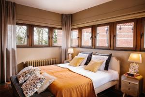 um quarto com uma cama grande e janelas em Charmehotel Manoir Ogygia em Poperinge