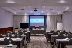 una sala de conferencias con mesas, sillas y una pantalla en Grecian Bay, en Ayia Napa