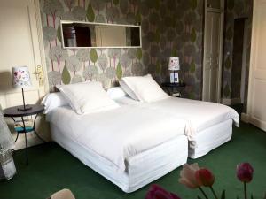 a bedroom with a white bed with a mirror and flowers at Chambres d'Hôtes Grand Bouy in Berry-Bouy