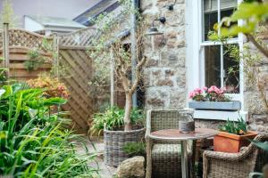 eine Terrasse mit einem Tisch, Stühlen und Pflanzen in der Unterkunft Headland House Luxury B&B in St Ives