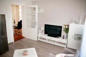 uma sala de estar branca com uma televisão e uma mesa em Apartment Sibenik with free parking em Šibenik