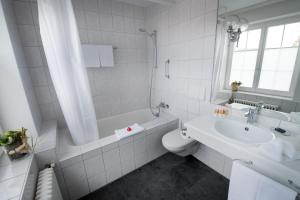 a white bathroom with a tub and a toilet and a sink at Gasthaus zum Bahnhof in Berg +21 photos