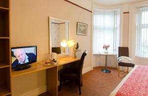 a bedroom with a desk with a television on it at Station Hotel Portsoy in Portsoy