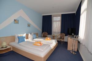 a hotel room with a bed with orange towels on it at Hotel Am Hohen Schwarm in Saalfeld