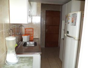 una pequeña cocina con fregadero y nevera. en Apartamento Boa Viagem, en Recife